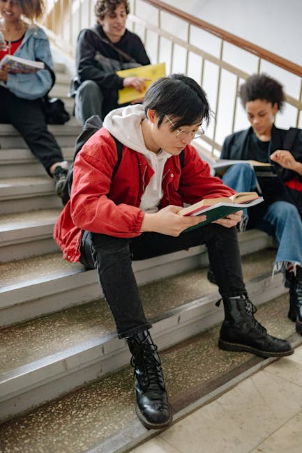 A diverse group of young adults reading and studying on indoor steps, focusing on academic collaboration.
