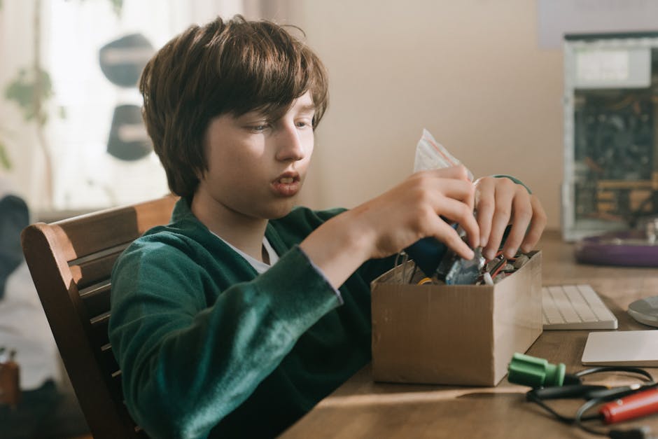 Young boy focused on exploring electronics components at a computer desk, embodying tech enthusiasm.